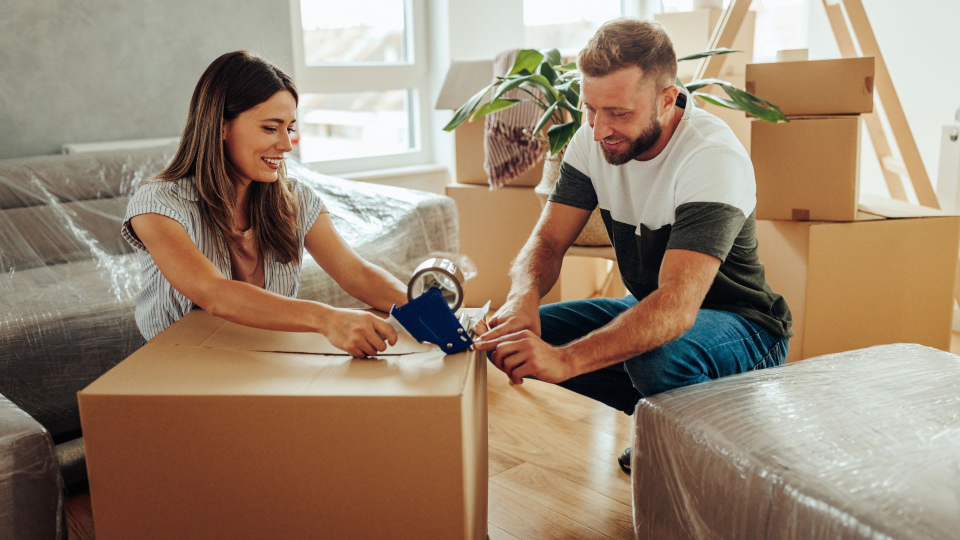 A couple packing for a move and talking about Step-by-Step Canadian Home Moving Guide for Buyers & Sellers