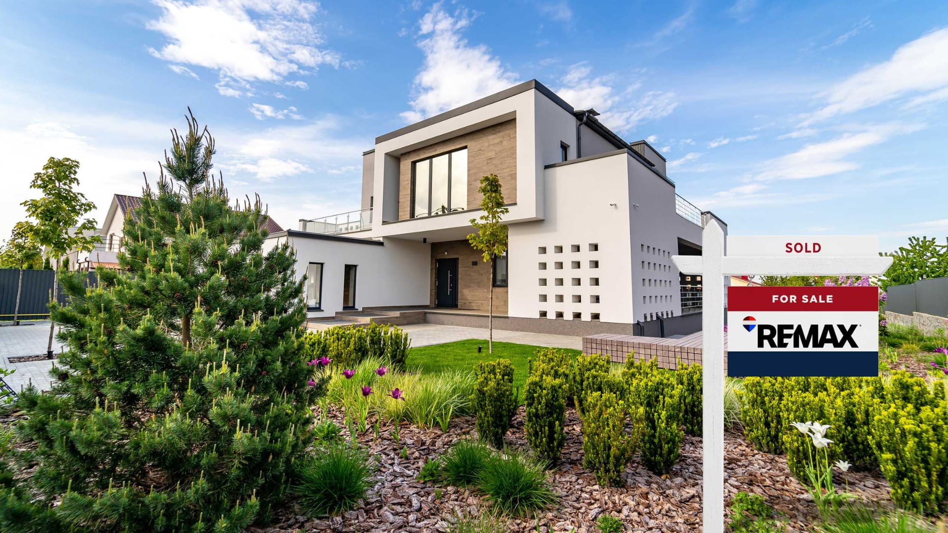 A modern home with lush green exterior being listed and sold by REMAX