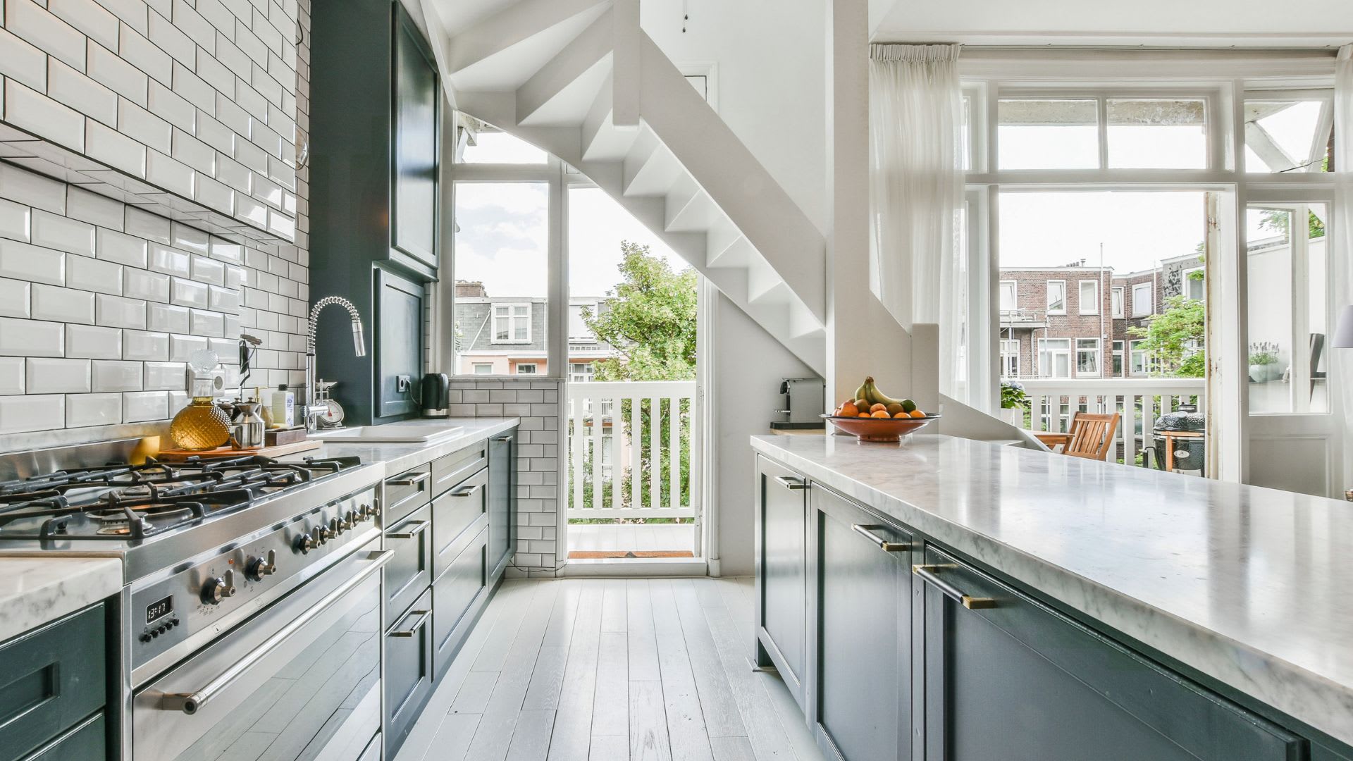 Invisible luxury buyers kitchen with marble counters and staircase to balcony