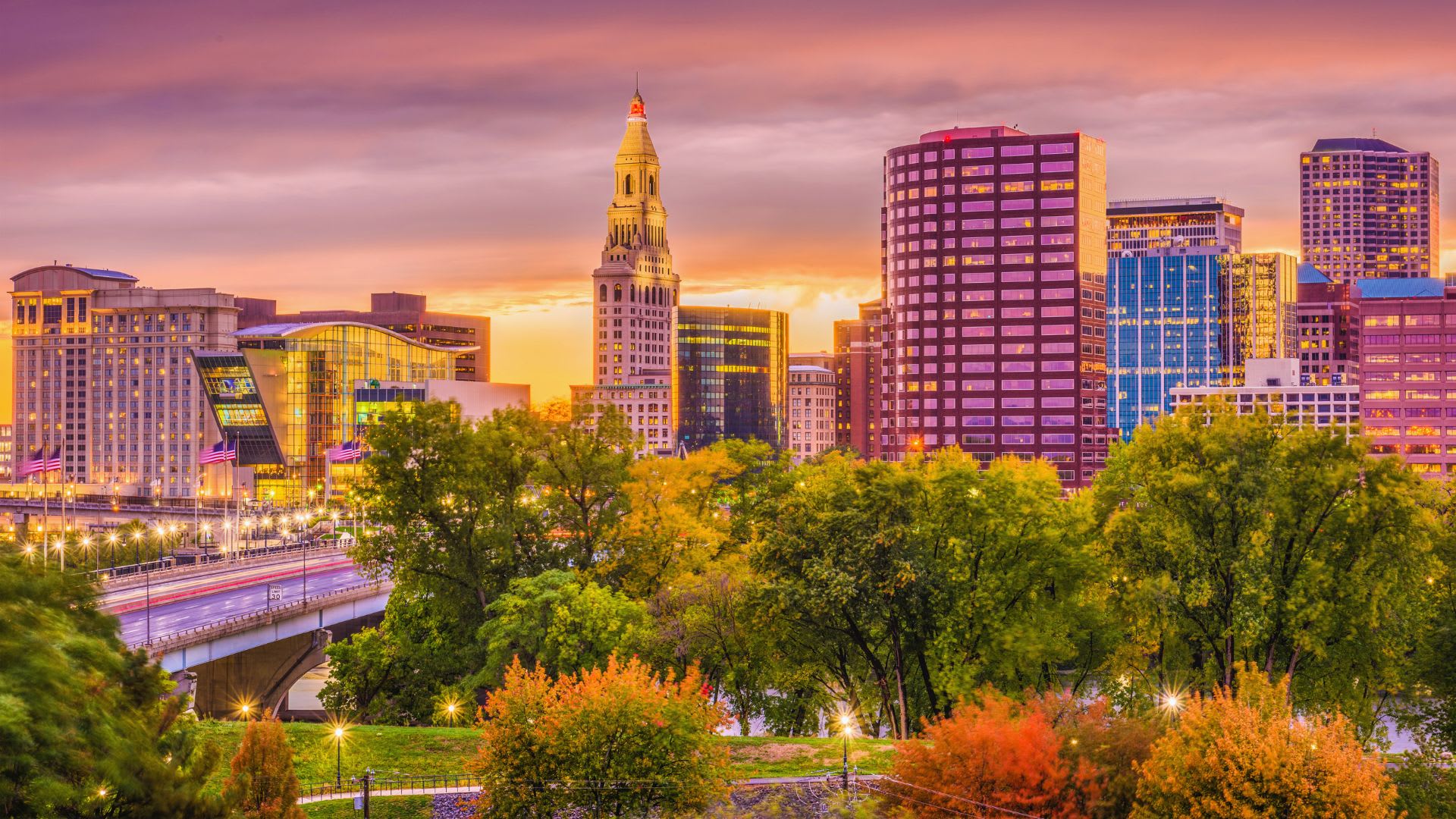 Downtown Hartford, CT skyline at sunset with fall foliage and a bridge over the Connecticut River