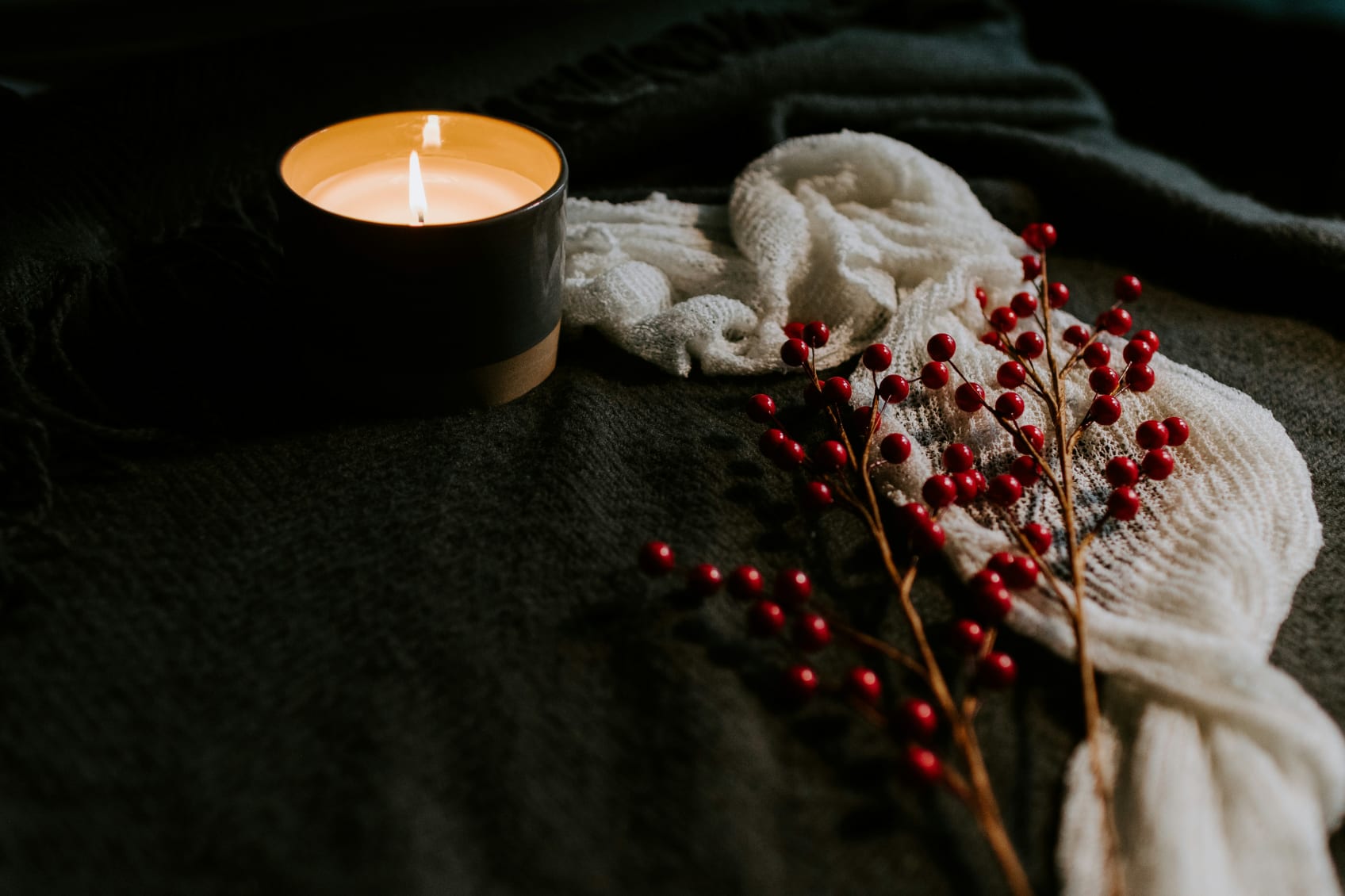 A candle with berries and a cloth