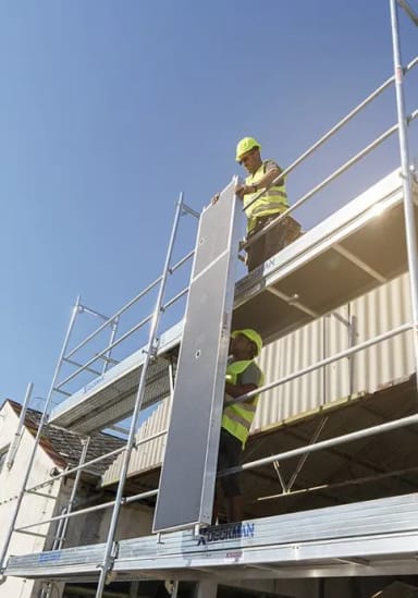 A man standing on a scaffold on top of a building