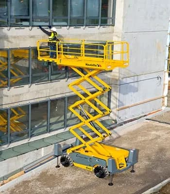 A man standing on a yellow scissor next to a building