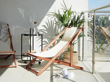 A white chair sitting on top of a balcony next to a potted plant