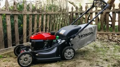A lawn mower sitting on the ground next to a fence