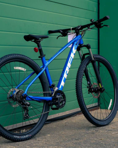 A blue mountain bike leaning against a green wall