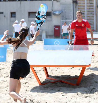 A woman holding a racquet on top of a sandy beach