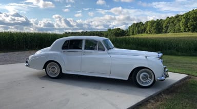 An old white car parked on a driveway