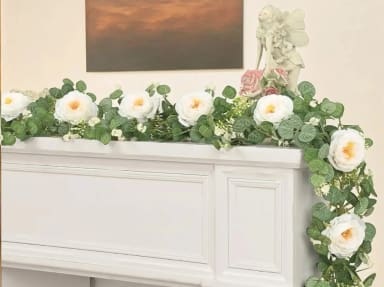A white fireplace with a bunch of flowers on top of it
