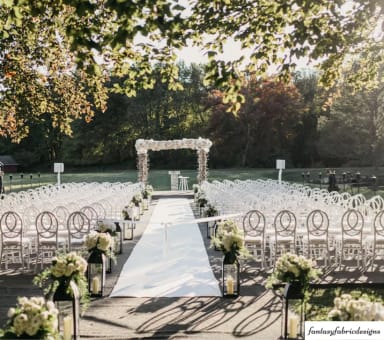 An outdoor ceremony setup with white chairs and white flowers