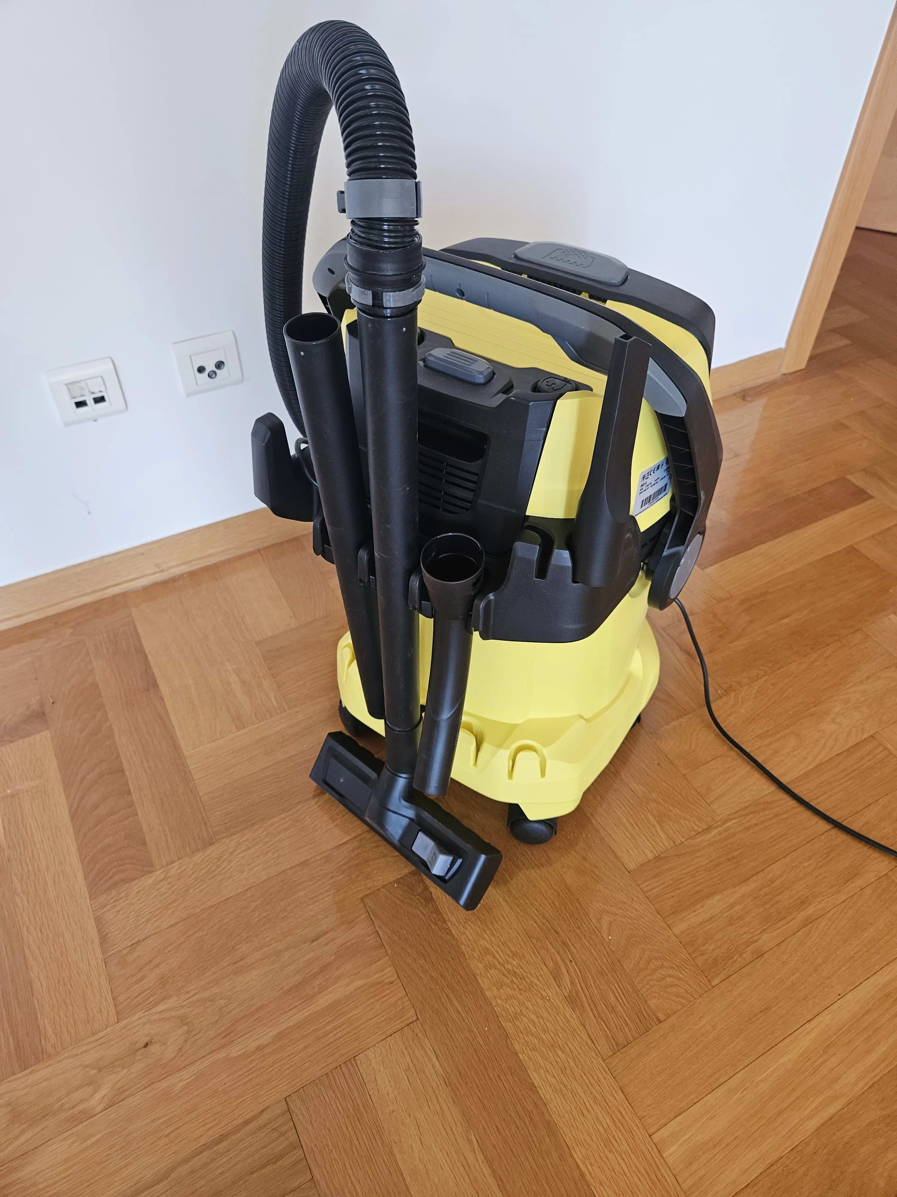A yellow and black vacuum sitting on top of a hard wood floor