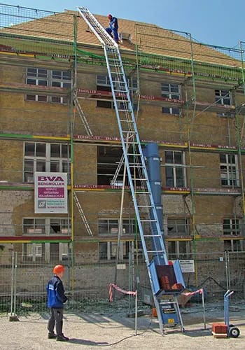 A man standing on top of a ladder next to a building