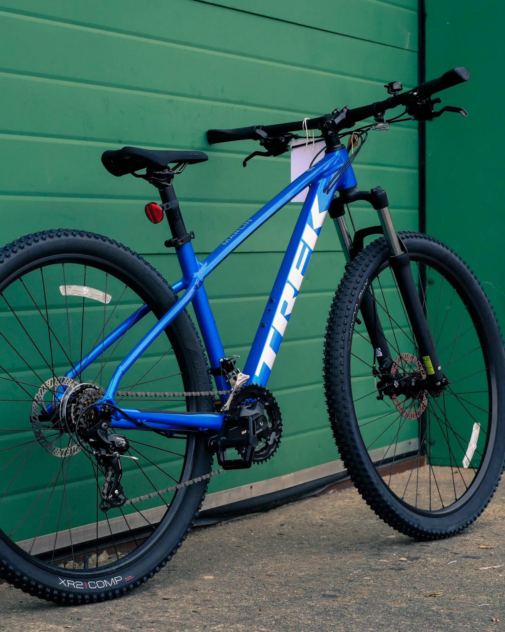A blue mountain bike leaning against a green wall