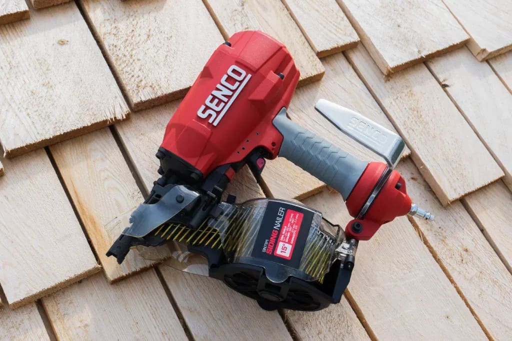 A cordless driller and a nail gun on a wooden surface