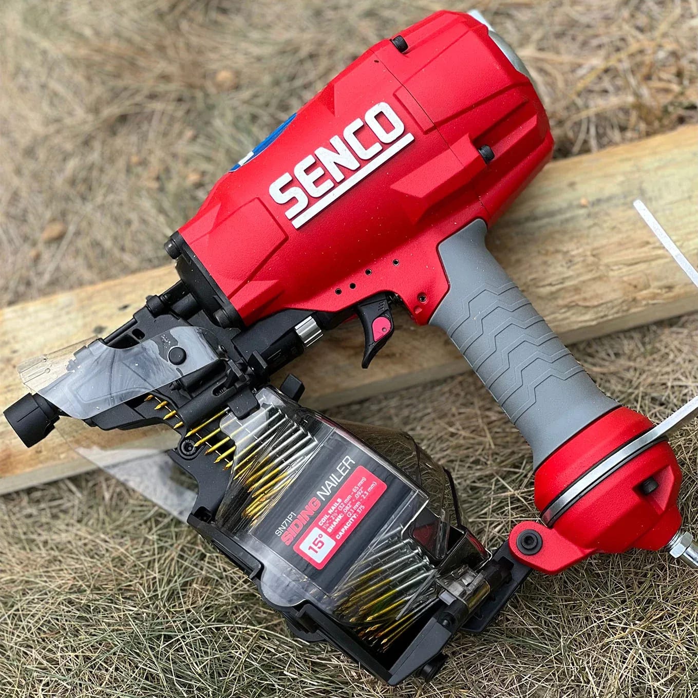 A red and black cordless driller and a piece of wood