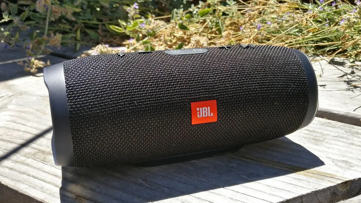 A black jbl speaker sitting on top of a wooden table