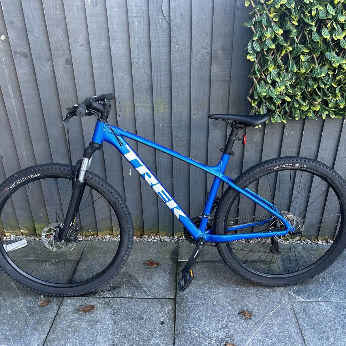 A blue mountain bike parked next to a wooden fence