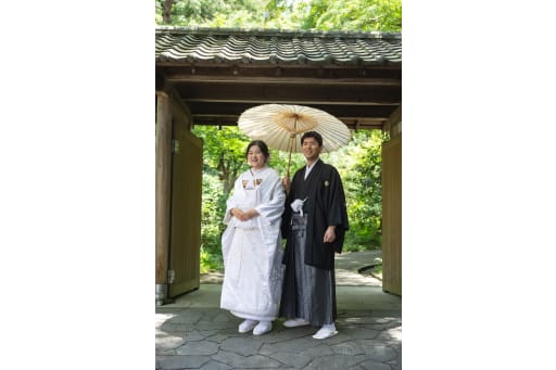 瓦屋根の立派な門の下で、和傘を差して
