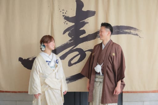 「寿」の暖簾の前で、楽しそうに視線を交わして