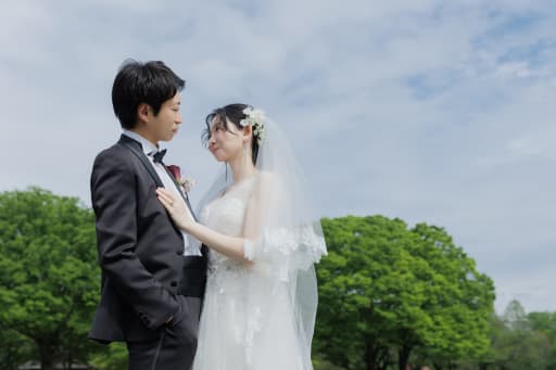 青空と緑をバックに、ベールをなびかせて向かい合う