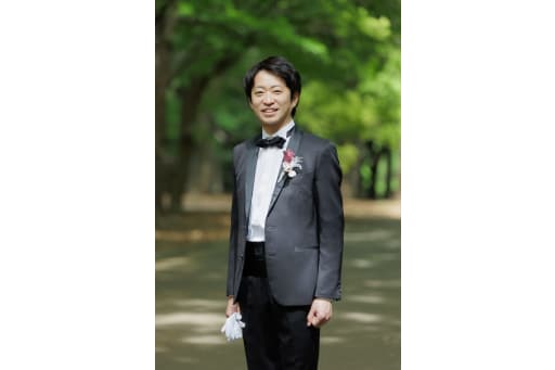 木々の緑に包まれて、タキシード姿でキリッと微笑む