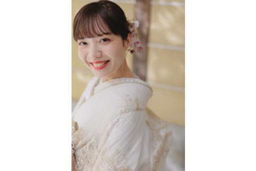 光を浴びてほほ笑む新婦の表情アップ