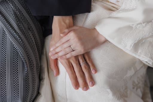 重ねた手に輝く、シンプルな結婚指輪