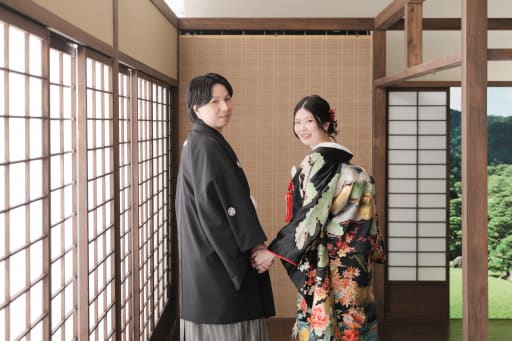 木のぬくもりと光が調和した屋内庭園。黒の紋付と色打掛がしっとりと映え、落ち着いた雰囲気に。