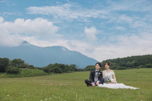 雄大な山並みを背に、草原で腰掛けて