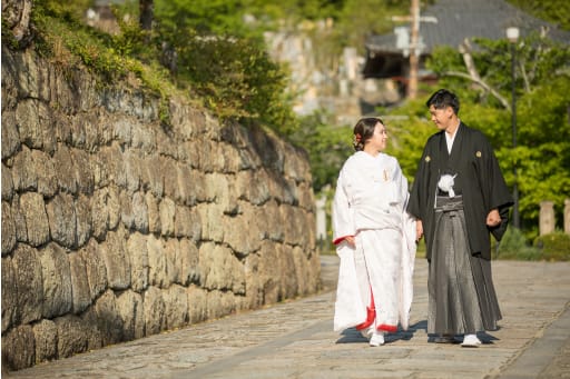 石垣の横をそぞろ歩く新郎新婦。