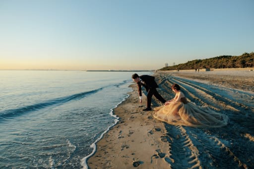 砂浜に何かを書き始めた新郎さん、そしてそれをやさしく見守る新婦さん。 おふたりのとっても素敵な関係が写真から伝わってきます。