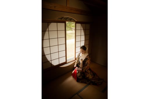 和室のまるい光に包まれた一枚。色打掛の柄が静かな空間にやさしく映えます。