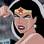 Diana with a tear down her cheek, in the rain, and with a raised fist and snarling at the enemy (from the Justice League animated show).