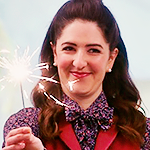 Janet smiling awkwardly and waving a small party flare.