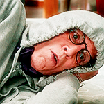 Michael lying down on the floor in shock with a hoodie on.