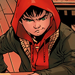 Damian in civil clothes, smirking. He has a red hoodie on and his arm is resting over a bar.