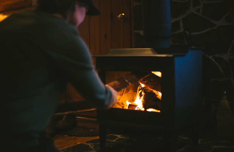 Stoking the wood stove in the cabin at Falcon Beach Ranch