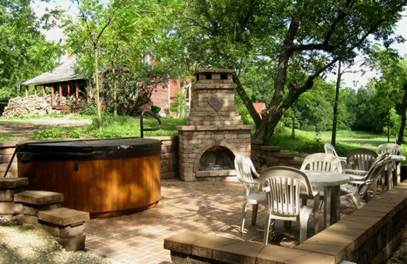 Fireside Patio at Red Cedar Lodge features a stone fireplace and large hot tub on a spacious patio for relaxing and entertaining.