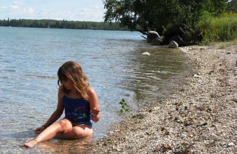 Kid sitting on beach at Trailhead Ranch.