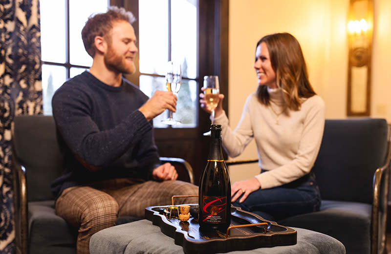 A young newlywed couple clang their wine glasses in celebration.