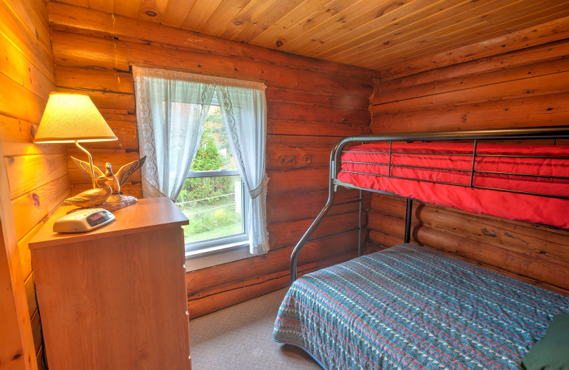 Meticulously clean country-style decorative 1920s authentic lakeside cedar log cabin bedroom at Jackson's Lodge and Log Cabin Village on international Lake Wallace, Canaan, Vermont.