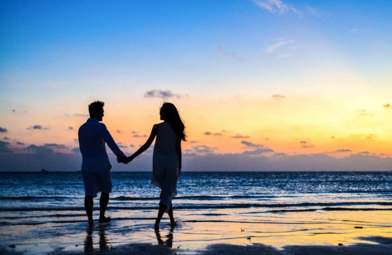 Couple holding hands on beach at Surfrider Resort.