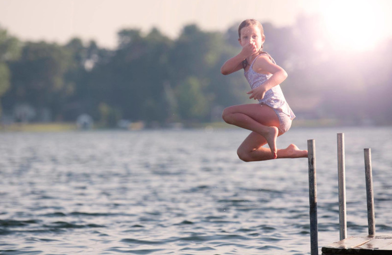 Kid jumping in lake at Great Blue Resorts- Shamrock Bay Resort.