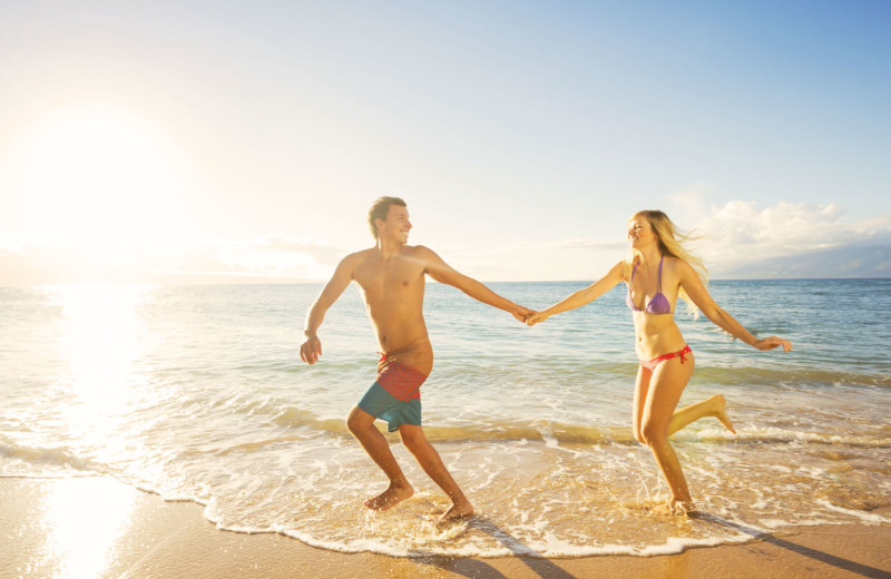 Couple holding hands running on beach near Southern Oaks Inn.