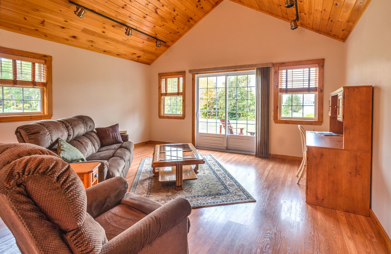 Meticulously clean country-style decorative chalet living room graced with cathedral ceiling, fully furnished kitchen and lake views at Jackson's Lodge and Log Cabin Village