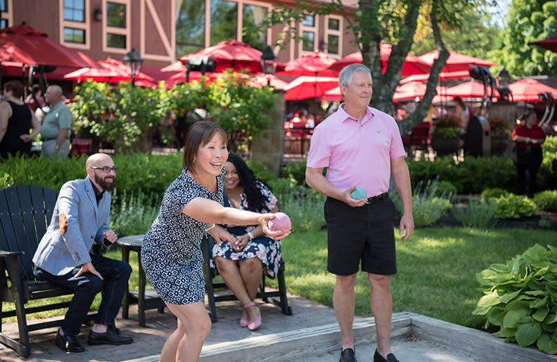 A man and woman playing bocce ball with friends and family.