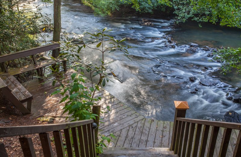 Rental deck by river at Blue Sky Cabin Rentals.