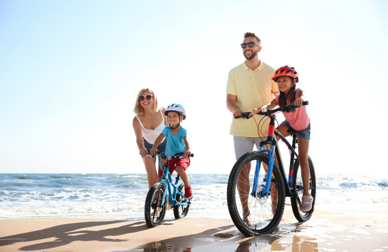 Family biking on beach at Boardwalk Realty Inc.