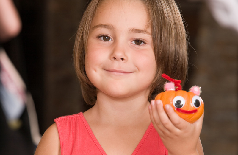 Child holding a mini jack-o-lantern.