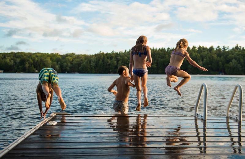 Kids jumping in lake at Blue Beaver Luxury Cabins.
